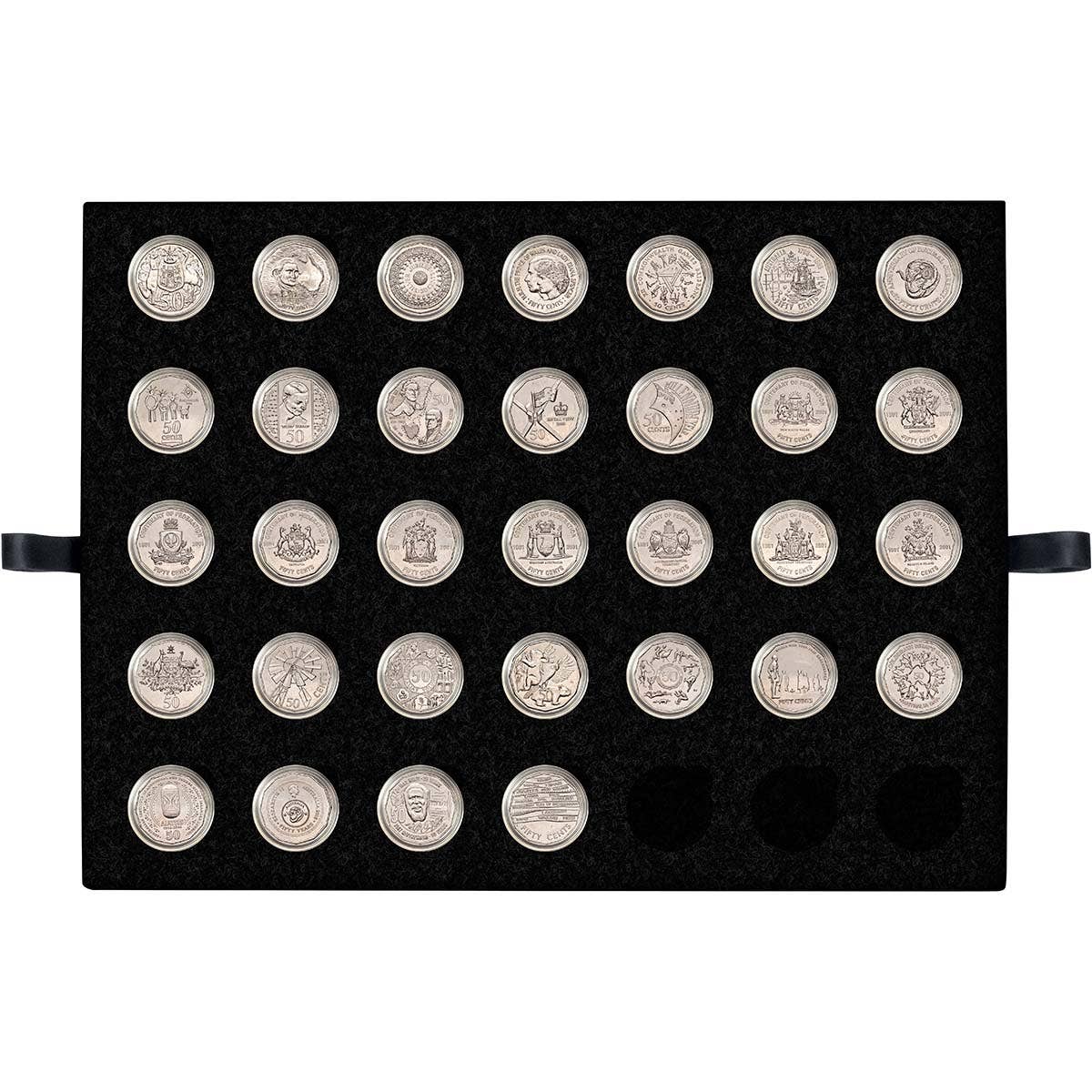 Overhead flat lay of several Australian 50 cent coins being examined with a jeweller's loupe alongside an open coin reference catalogue